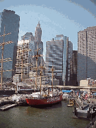 Top right you see the skyline of NYC at South Street Seaport. The South Street Seaport Historic District encompasses an 11 block area fronting the East River. Here you can visit historic ships, dine and shop in a large mall on the pier.